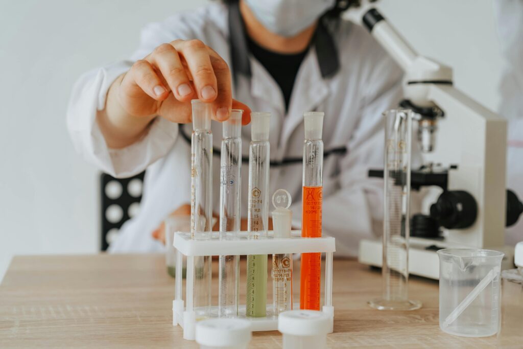 pexels-photo-8531346-8531346 Scientist in lab coat conducting an experiment with test tubes and a microscope.